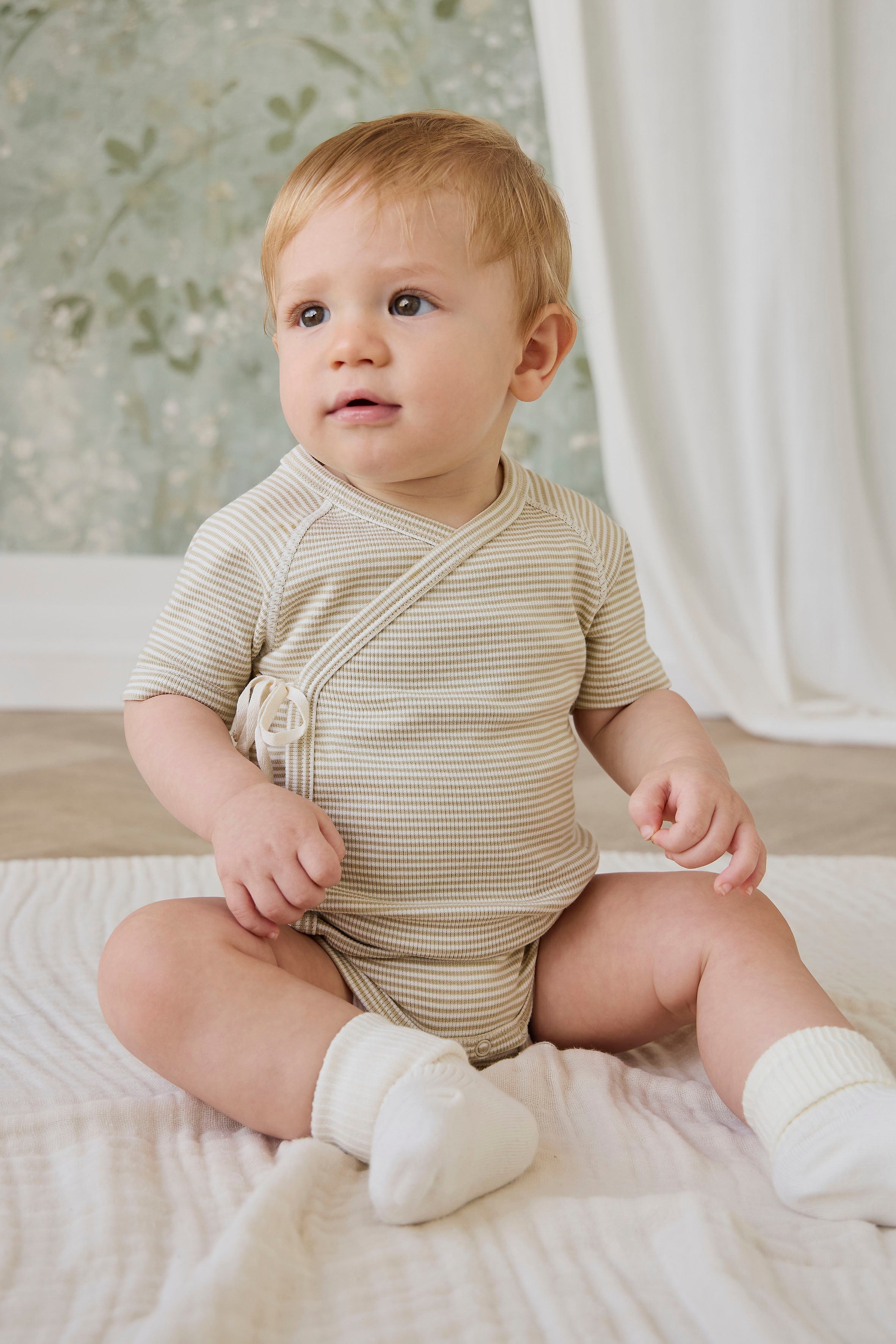Combinaison courte bébé en coton côtelé fin à rayures crème et marron, avec ouverture cache-cœur et liens sur le côté pour le confort quotidien