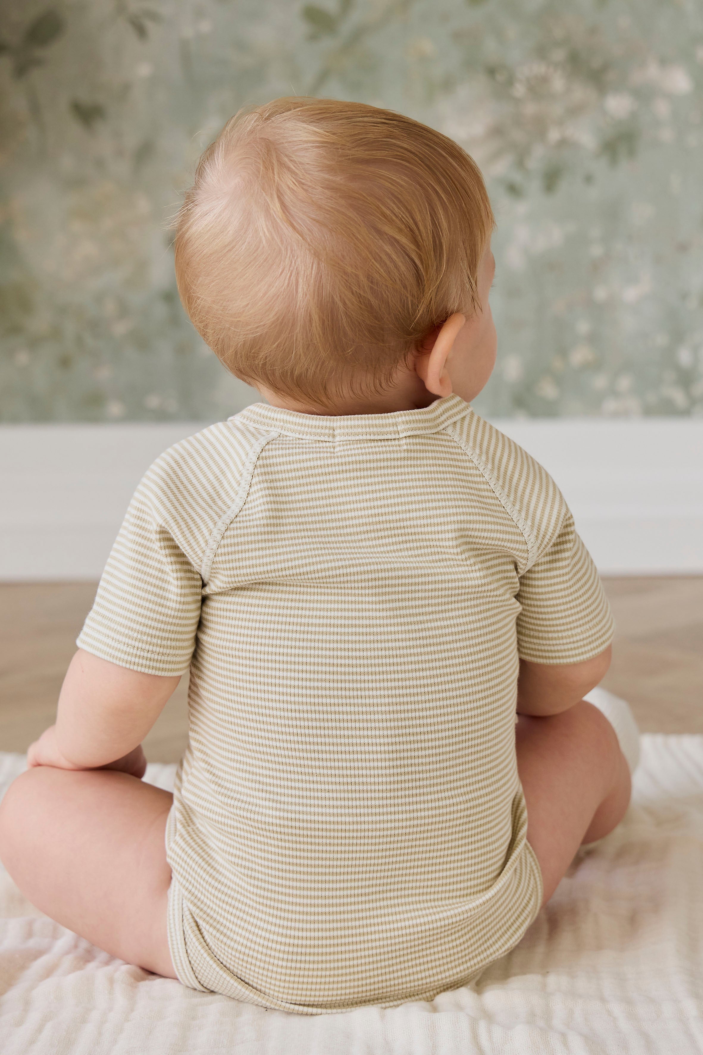 Combinaison courte bébé en coton côtelé fin à rayures crème et marron, avec ouverture cache-cœur et liens sur le côté pour le confort quotidien