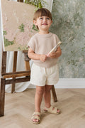 Gilet en maille pur coton, coloris sable neutre uni, à texture côtelée et manches courtes pour enfants. Idéal pour superposer ou un style décontracté.
