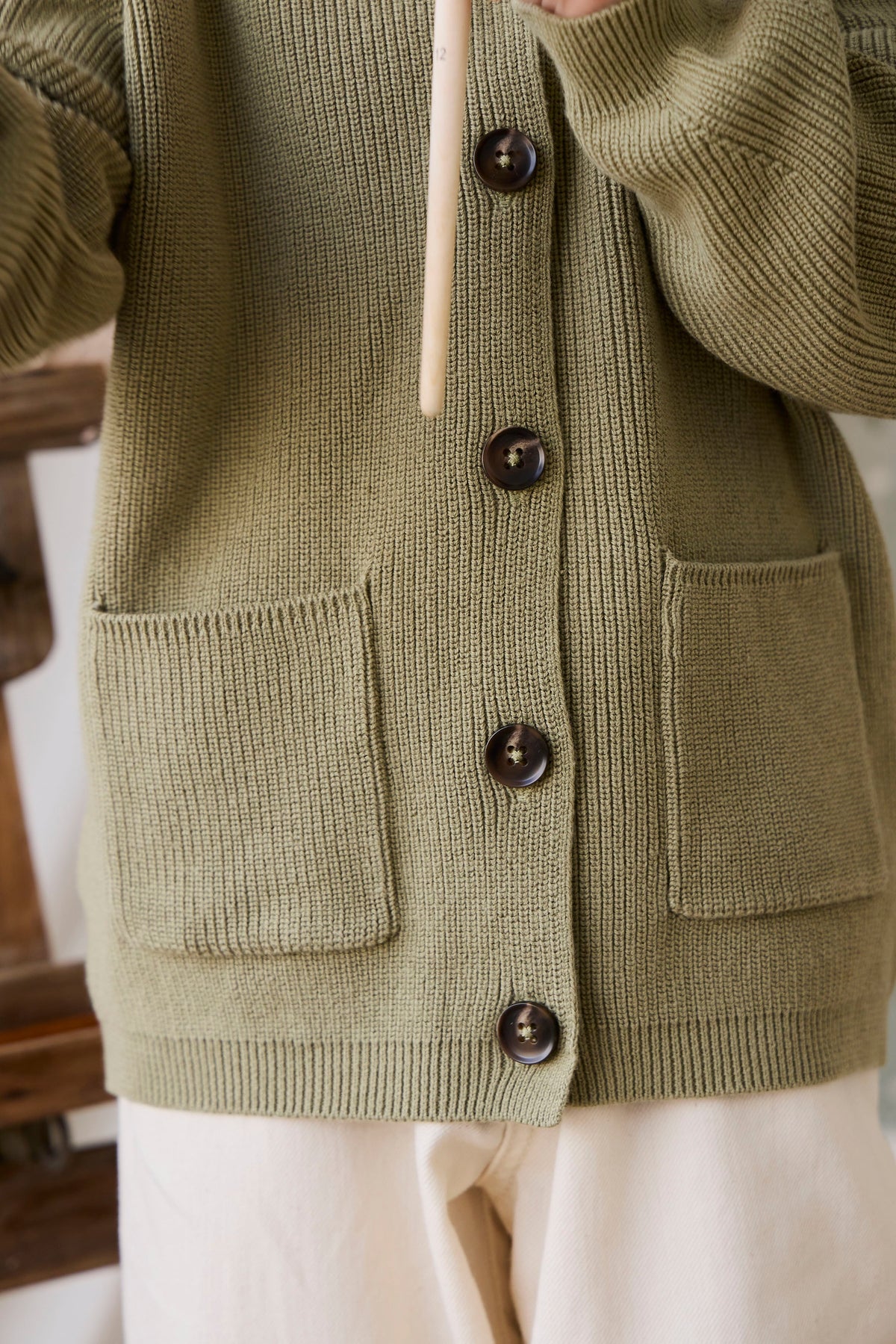 Classique = Veste en tricot de coton uni vert avec boutonnage sur le devant, poches plaquées et ourlet côtelé pour enfants
