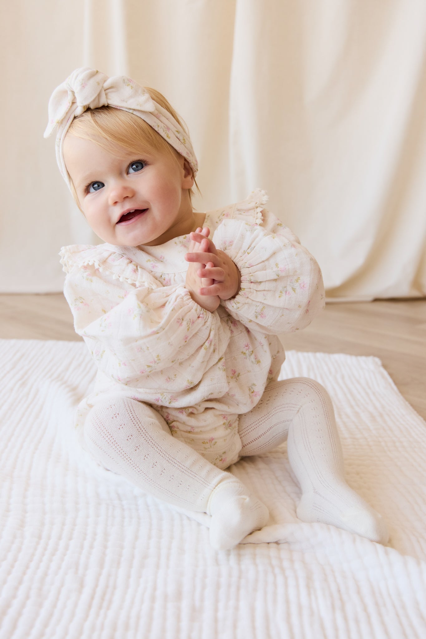 Barboteuse bébé en mousseline de coton bio à imprimé floral bohème crème, rose et vert, avec corsage froncé et ouvertures de jambes élastiquées pour temps chaud