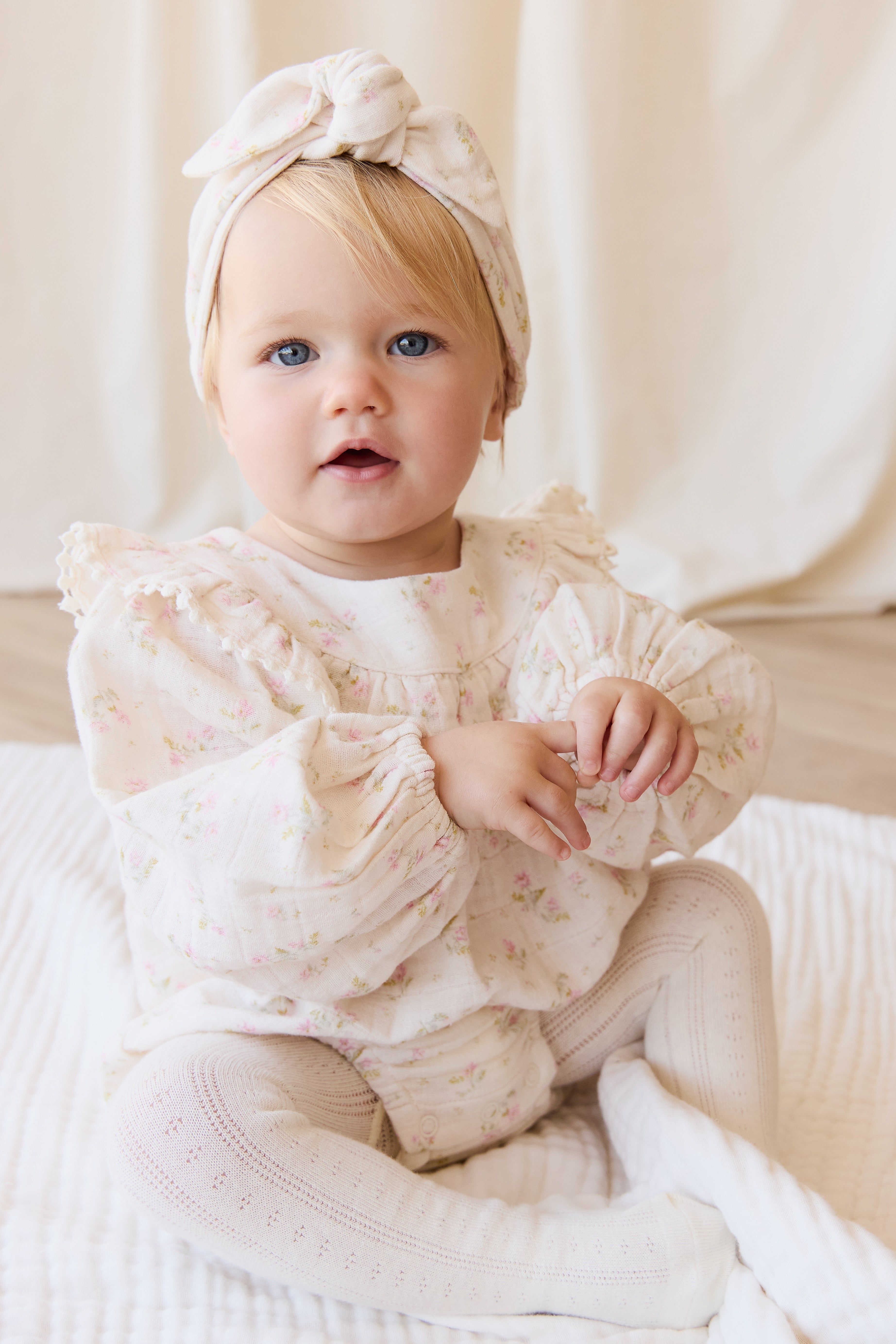 Barboteuse bébé en mousseline de coton bio à imprimé floral bohème crème, rose et vert, avec corsage froncé et ouvertures de jambes élastiquées pour temps chaud