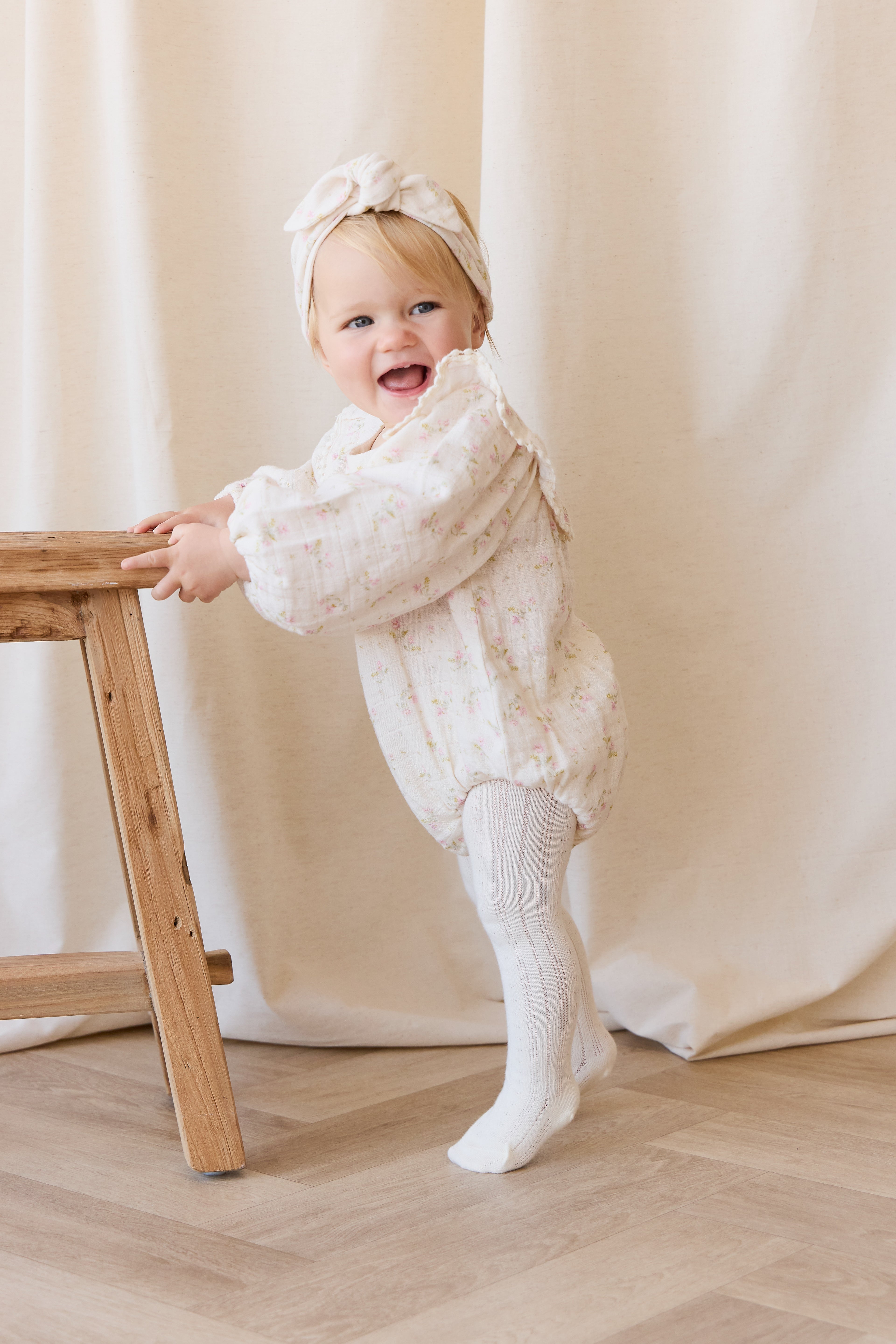 Barboteuse bébé en mousseline de coton bio à imprimé floral bohème crème, rose et vert, avec corsage froncé et ouvertures de jambes élastiquées pour temps chaud
