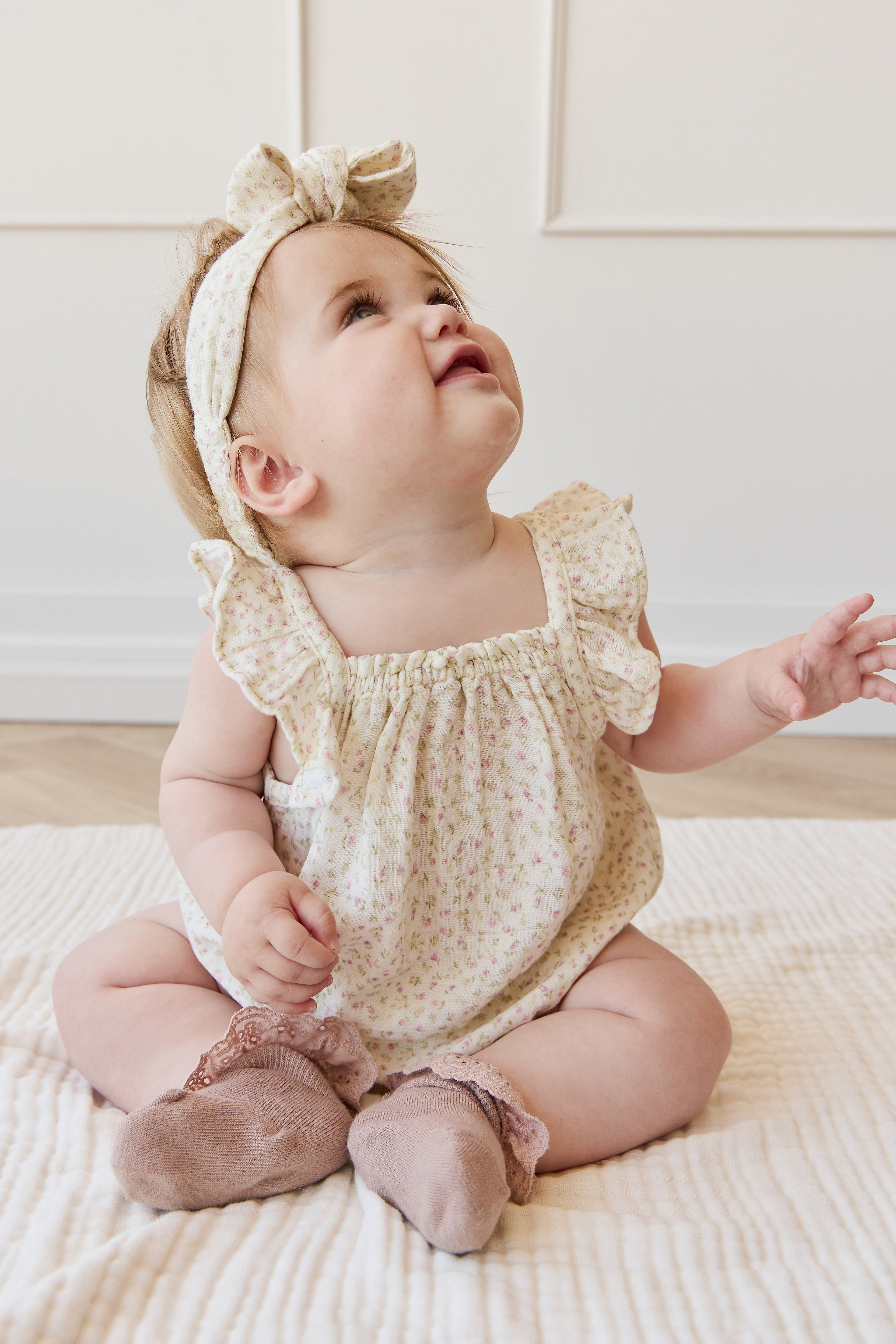 Barboteuse bébé en mousseline de coton biologique imprimé floral rose bohème, coupe décontractée, tissu respirant, idéale pour les jeux par temps chaud.