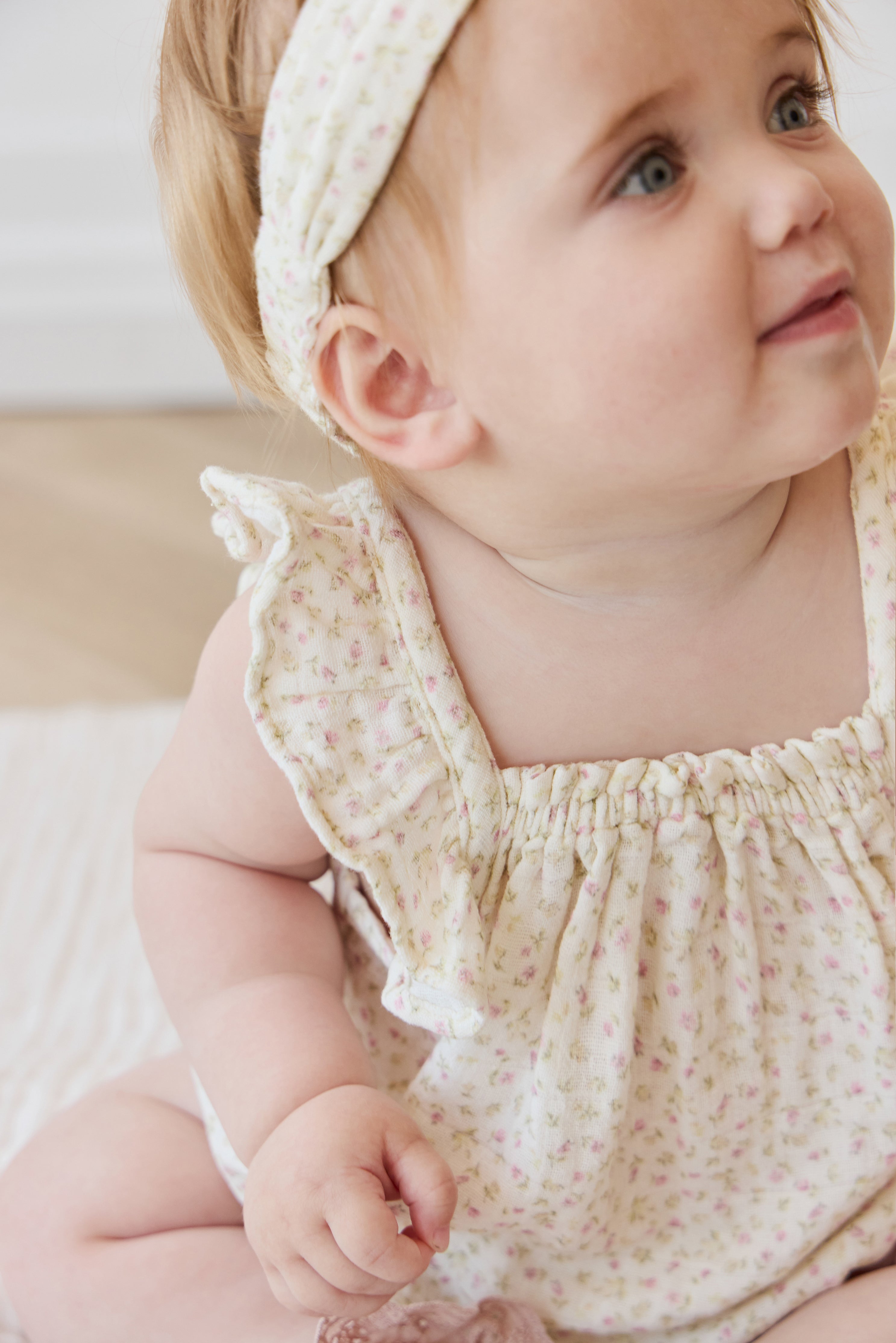 Barboteuse bébé en mousseline de coton biologique imprimé floral rose bohème, coupe décontractée, tissu respirant, idéale pour les jeux par temps chaud.
